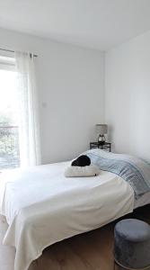 a white bedroom with a bed with a cat on it at Apartment Tree House in Lovran