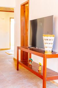 une table avec une télévision et un vase sur une étagère dans l'établissement Refugios Parajuru - Villa Palmeira, à Beberibe