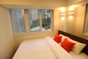 um quarto com uma cama com almofadas vermelhas e uma janela em Philstay Dongdaemun Economic em Seul