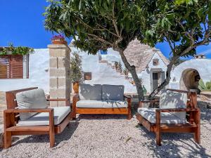 a group of three chairs sitting next to a tree at Trullo a ll'éra in Ceglie Messapica