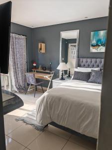 a bedroom with a large bed and a desk at Tranquil Pool View in Cape Town
