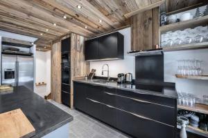 - une cuisine avec comptoirs noirs et plafonds en bois dans l'établissement Residence La Canadienne - Pièces 524, à Val dʼIsère