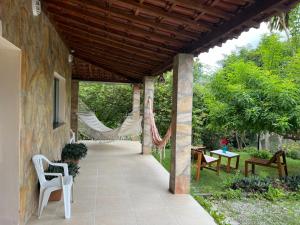 a covered patio with chairs and a hammock at Pousada Encanto dos Mognos in Ibicoara