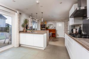 a kitchen with white cabinets and a large window at 15 Foster Crescent in Troon