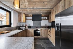 cocina con armarios de madera y nevera de acero inoxidable en Résidence La Tapia - Chalets pour 14 Personnes 364 en Val dʼIsère