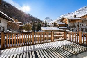 einen Holzzaun auf einem Balkon mit schneebedeckten Bergen in der Unterkunft Résidence La Tapia - Chalets pour 14 Personnes 364 in Val dʼIsère