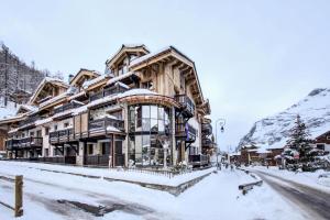 un grand bâtiment en bois dans la neige dans l'établissement Residence La Canadienne - 5 Pièces pour 8 Personnes 624, à Val dʼIsère