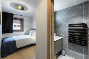 een slaapkamer met een bed en een badkamer met een wastafel bij Résidence Stallion A - 3 Pièces pour 4 Personnes 464 in Megève