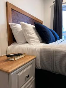 a bed with blue and white pillows and a wooden headboard at 53 Luxury Rooms in Maynooth