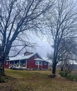 a red barn in a field with two trees at Country relaxation in Naches