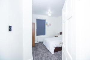 een witte slaapkamer met een bed en een raam bij Lovely City Home + Free Parking in Manchester