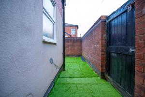 an empty alley with a door and green grass at Lovely City Home + Free Parking in Manchester