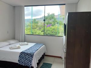 a bedroom with a bed and a large window at Pousada Encanto dos Mognos in Ibicoara