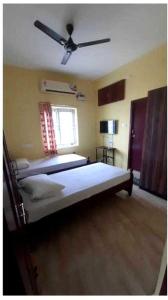 a bedroom with two beds and a ceiling fan at SPOT ON Shappy Inn Koyambedu Near PVR SPI Palazzo Chennai in Chennai