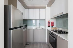 a kitchen with white cabinets and a stainless steel refrigerator at Fresh & Quiet 1BR at Midtown Noor 4 Tower in Dubai