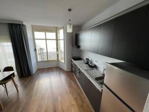 a kitchen with black cabinets and a wooden floor at Wave Beachfront Apartments in Durrës