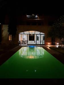 a swimming pool with green illumination at night at Villa de vos rêve in Marrakesh