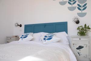 een bed met een blauw hoofdeinde en witte lakens en kussens bij Buen Aire in Cagliari