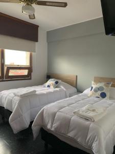1 dormitorio con 2 camas con sábanas blancas y ventana en Hotel Bahia, en La Paloma