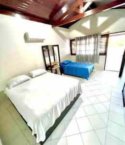 um quarto com uma cama branca e um sofá azul em Casa em Praia do Francês - Alagoas. em Marechal Deodoro