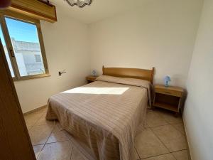 una piccola camera da letto con un letto e una finestra di Appartamenti al mare Torre Pali by Ionian Travel a Torre Pali
