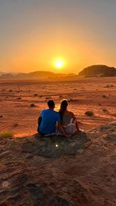 a man and woman sitting in the desert watching the sunset at Wadi rum Rozana camp in Wadi Rum