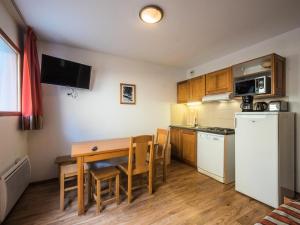 una pequeña cocina con mesa y nevera en Appartement 2 Pièces Cabine 6 Personnes - été 324, en Orcières