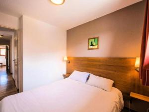 una camera con letto bianco e testiera in legno di Appartement 2 Pièces Cabine 6 Personnes - été 324 a Orcières