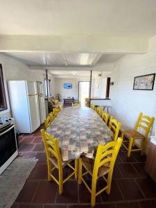 comedor con mesa grande y sillas amarillas en Casa Dunas, en Passo de Torres