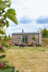 a small house in the middle of a field at Coldharbour Luxury Shepherds Hut in Stone