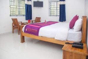 a bedroom with a large bed with two chairs at Flagship Key 2 Heaven in Ooty