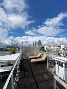 a balcony with two couches and a view of a city at Penthouse Luxueux avec Terrasse Panoramique in Boulogne-Billancourt