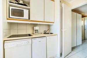 een keuken met witte kasten en een magnetron bij Résidence le Hameau de Cap Esterel - maeva Home - Appartement 2 pièces 5 p 571 in Saint-Raphaël