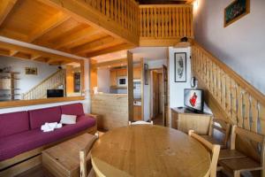 a living room with a purple couch and a wooden table at Résidence Les Cimes Blanches - Studio pour 5 Personnes 494 in Courchevel