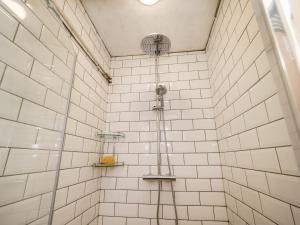 ein Bad mit einer Dusche und weiß gefliesten Wänden in der Unterkunft Finest Retreats - The Old Sunday School & Vestry in Cromer