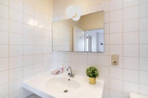 ein weißes Badezimmer mit Waschbecken und Spiegel in der Unterkunft Bright Apartments In The Heart Of Antwerp in Antwerpen