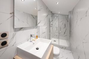 een witte badkamer met een wastafel en een douche bij Résidence Le Chamois - 3 Pièces pour 6 Personnes 794 in Courchevel