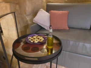 uma mesa com uma garrafa de vinho e um prato de comida num sofá em Suite San Biagio nei sassi em Matera