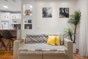 - un salon avec un canapé et des oreillers jaunes dans l'établissement Flores da Montanha Centro by Achei Gramado, à Gramado