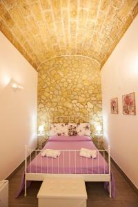 ein Schlafzimmer mit einem lila Bett und einer Steinmauer in der Unterkunft La casa di Marilù in Marsala
