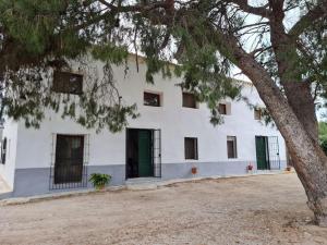 a white building with green doors and a tree at El Cabezo de la Torre in Cieza