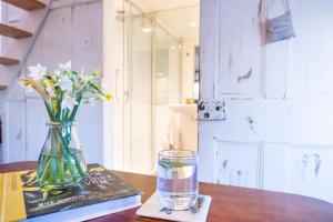 um vaso de flores e um livro e um copo de água em Luxury self-contained cottage for two with hot tub em Staverton