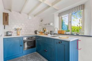 uma cozinha com armários azuis e uma janela em Luxury self-contained cottage for two with hot tub em Staverton