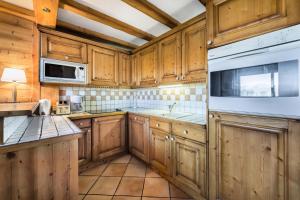 una cocina con armarios de madera y un aparato blanco en Résidence Balcons De Pralong - 4 Pièces pour 6 Personnes 064, en Courchevel