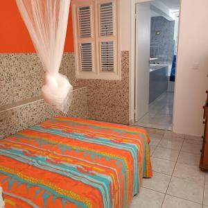 a bedroom with a bed with a colorful blanket at Maison charmante au cœur de Le Gosier avec cheminée in Le Gosier