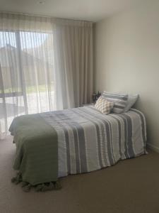 a bedroom with a bed with a striped blanket and a window at Mountain Views, Remarkable in Queenstown