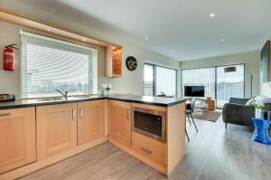 uma cozinha com armários de madeira e uma sala de estar em Fenwick Chambers by Week2Week em Gosforth