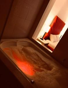 d'une baignoire avec du liquide rouge à côté d'un lit. dans l'établissement Hotel Opera, Centro Medellín, Entertainment,Y Bar, Solo Adultos, à Medellín