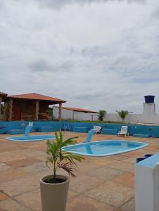 uma piscina com duas cadeiras e uma planta num vaso em Chalés Passagem do Canto em Barreirinhas