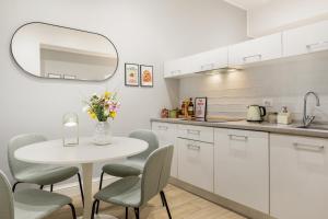 cocina blanca con mesa blanca y sillas en Homs Boutique Apartment, en Roma